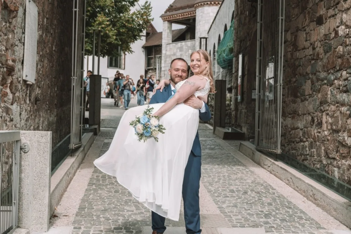 Poročna fotografija mladoporočencev; ujet pristen trenutek z naravno svetlobo in umirjeno kompozicijo v dokumentarnem slogu.